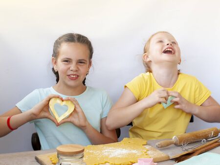Two children a girl make cookies from dough. Two funny cheerful girls. Natural homemade food.の写真素材