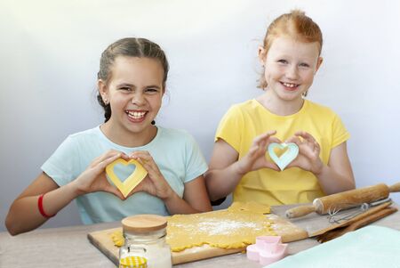 Two children a girl make cookies from dough. Two funny cheerful girls. Natural homemade food.の写真素材