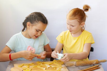 Two children a girl make cookies from dough. Two funny cheerful girls. Natural homemade food.の写真素材