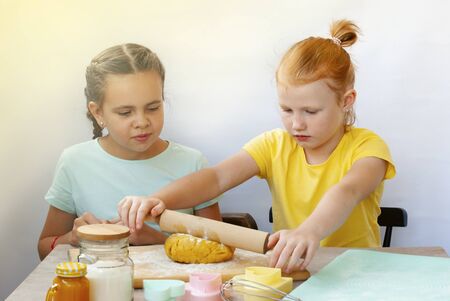Two children a girl make cookies from dough. Two funny cheerful girls. Natural homemade food.の写真素材
