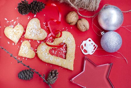 Christmas composition with glass star, biscuits, pine cone, nuts and decorations on a red background.の写真素材