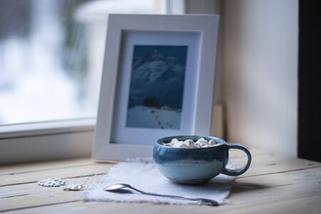 A cup of cacao with marshmellows and christmas decoration on the table with colorful background....