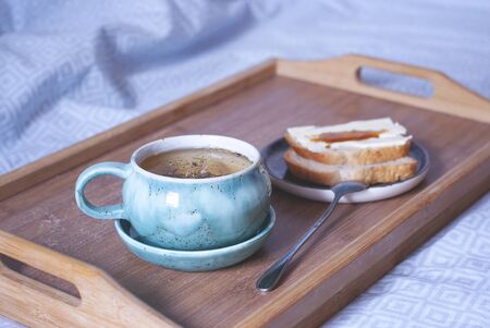 Breakfast in the bed. Big cup of tea on a tray. Comfort of home atmosphere.の写真素材