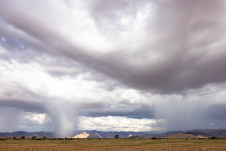Rain start falling from the clouds over the Namib Desert in Namibiaの写真素材