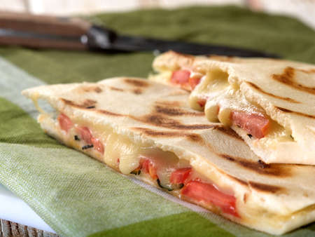 Melted Caprese pita bread sandwich on green and white napkin