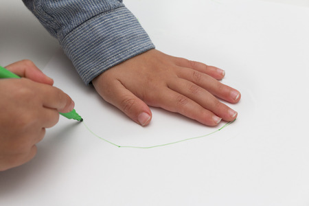 child holding pen on blank sheet of paper. kid draws on blank paperの写真素材