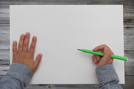 kid holding pen on blank sheet of paperの写真素材