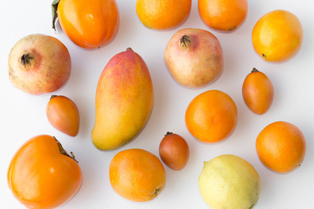 Many fresh orange fruits on white background - orange, mango, lemon, kakiの写真素材
