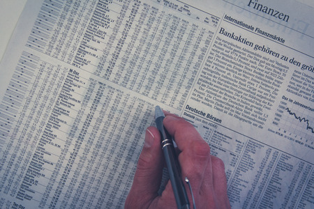 hand holding pen over german financal part of newspaperのeditorial素材