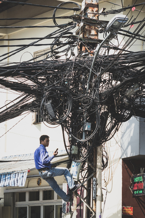 Saigon, Vietnam - January 20, 2014: Electrician fixing messy cables on telephone mast.のeditorial素材