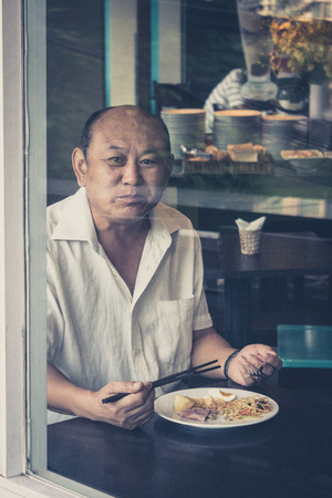 Saigon, Vietnam - February 11, 2014: Portrait of an old man having breakfast in a restaurant.のeditorial素材
