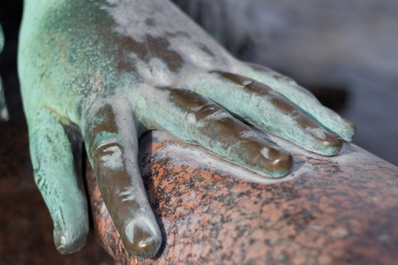metal hand of an old bronze statue laying onの写真素材