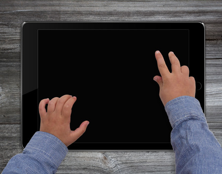 child hands on  tablet computer with blank screen on wooden deskの写真素材