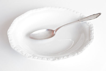 empty plate with silver spoon isolated on white backgroundの写真素材