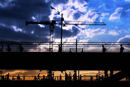 silhouettes of many people crossing bridge with sunset sky backgroundの写真素材