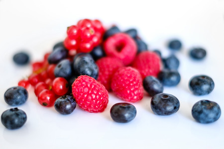 pile of mixed berries,  berry fruits on white background - rasberries, blueberries and currantの写真素材