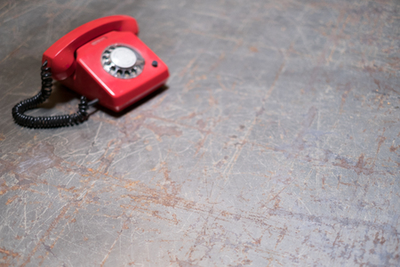 empty vintage table with red phone in background - telephone on deskの写真素材