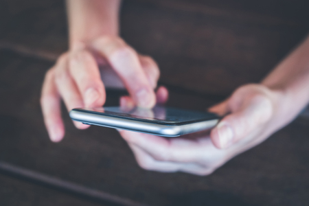 hands holding phone macro - girl uses smartphone closeup -の写真素材