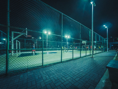 people playing soccer at night on sports field in city -の写真素材
