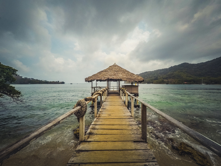 wooden pier with a sheltered hut on ocean coast on a cloudy dayの写真素材