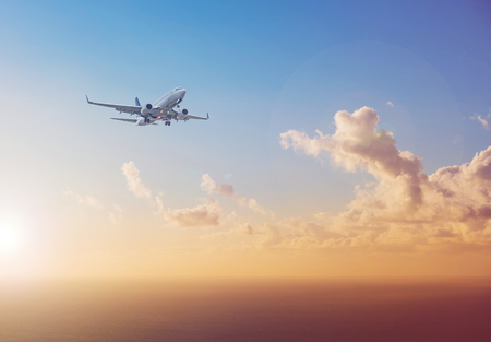 airplane flying above  ocean with sunset sky background   - travel conceptの写真素材