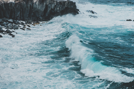 waves hitting coastling - black cliff on ocean coast