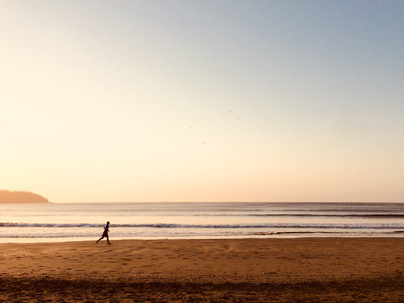 person running on beach during sunset - jogger at ocean  -の写真素材