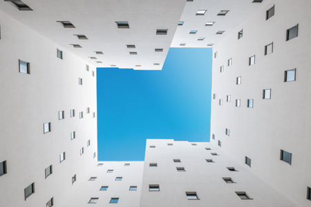 looking up inside apartment building courtyard - building facade, court and blue sky  -