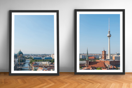 two framed pictures of Berlin skyline on wooden floor white wall background