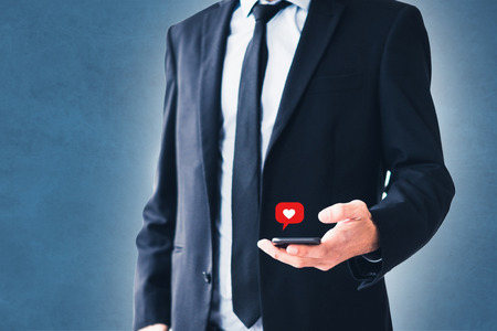 social media like notification icon on phone - man using smartphoneの写真素材