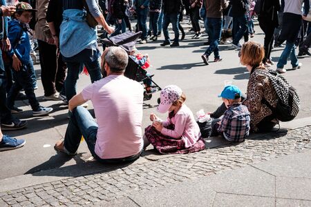 Young family with children sitting on sidewalk on street parade on laboratory day in Berlinのeditorial素材