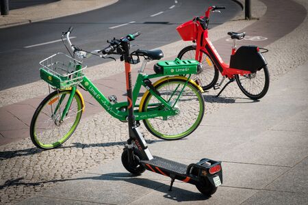 Bike sharing bicycles and electric scooter, escooter or e-scooter on sidewalk in Berlin, Germanyのeditorial素材