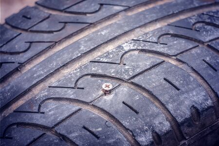 Closeup of flat car tire punctured with a screwの写真素材