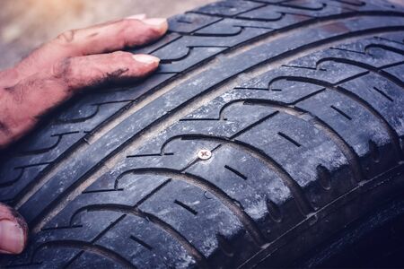 Hands on flat car tire punctured with a screw closeup -