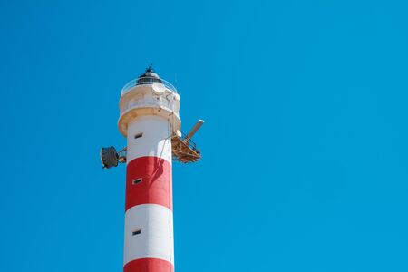 red,white lighthouse tower isolated on blue skyの写真素材