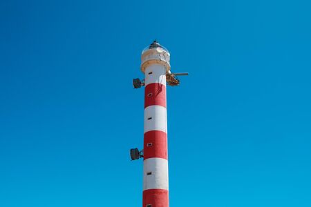 red,white lighthouse tower isolated on blue skyの写真素材