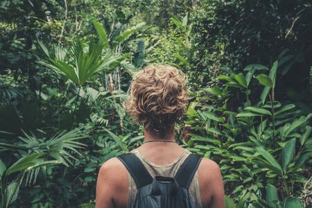 young woman with backpack hiking in tropical jungle / rainforest -
