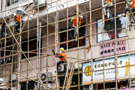 Hong Kong, November, 2019: Workers on construction site building bamboo scaffolding on house facade in Hong Kongのeditorial素材