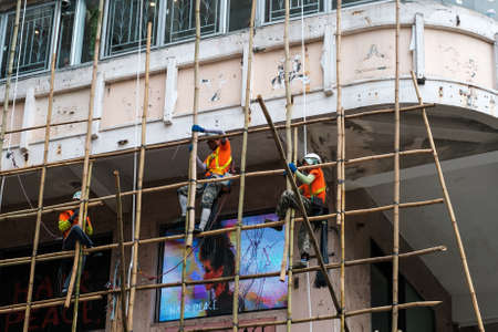 Hong Kong, November, 2019: Workers on construction site building bamboo scaffolding on house facade in Hong Kongのeditorial素材