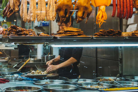 Hong Kong - November, 2019: Chinese restaurant chef preparing food behind shop windowのeditorial素材