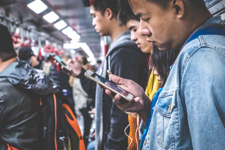 HongKong, China - November, 2019: People looking on mobile phone inside MTR train / subway train in HongKongのeditorial素材