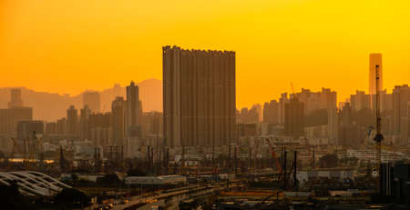 city skyline, skyscrapers, construction cranes and sunset sky in Hong Kong