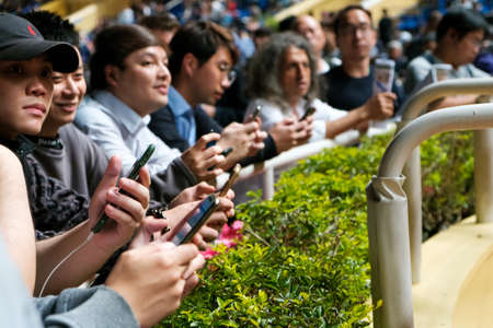Hong Kong, November, 2019: People looking on mobile phone at Horse racing course in Hong Kong Jockey Clubのeditorial素材