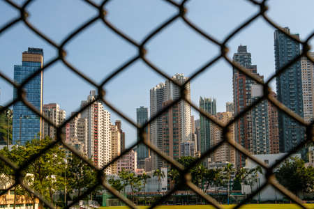 Skyscraper buildings and skyline of Hong Kong behind fence -