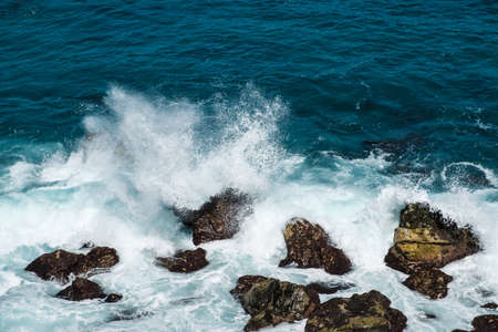 rough ocean waves crashing on rocks at coast or beachの写真素材
