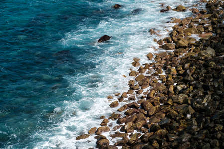 ocean waves hitting black stone beach, rocky coast landscapeの写真素材