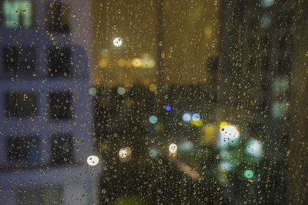 Shallow DOF of water drops on glass with bokeh and apartment building on background