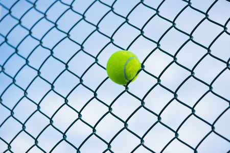 Tennis ball on metal wire against sky. Concept of tennis protection equipmentの写真素材