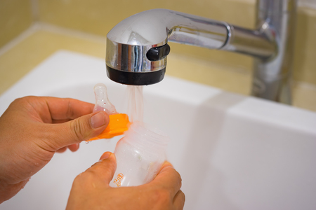 Asian father hand washing newborn milk bottle under waterの写真素材