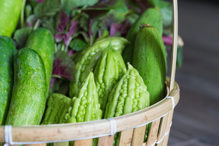 Tropical green organic vegetable on basket on wooden backgroundの写真素材